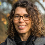 Foto Marina Andres. Frau mit braunen Locken, lächelnd