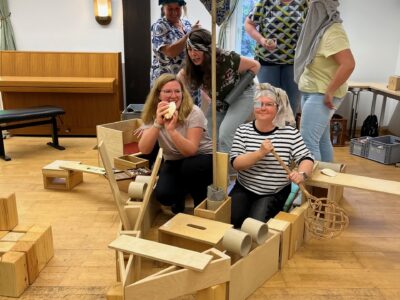 Mensch in einem selbstgebastelten Boot mit Hölzern, Karton, Tüchern & Klorollen. Bauen, Konstruieren in der Kita